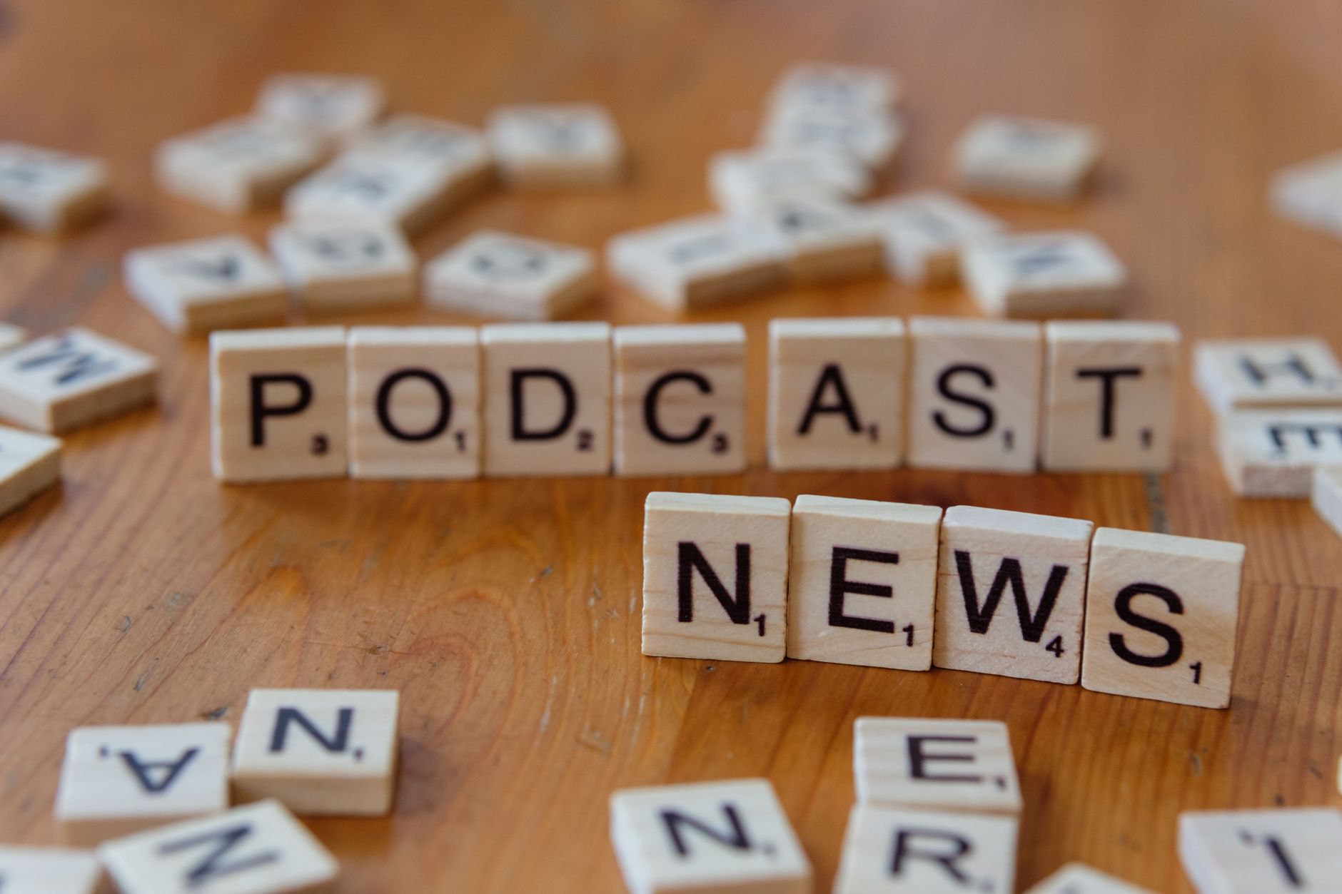 Wooden letter tiles spelling out 'PODCAST NEWS' on a wooden surface. — Coolzino Casino change-t-il la donne avec ses incentiv