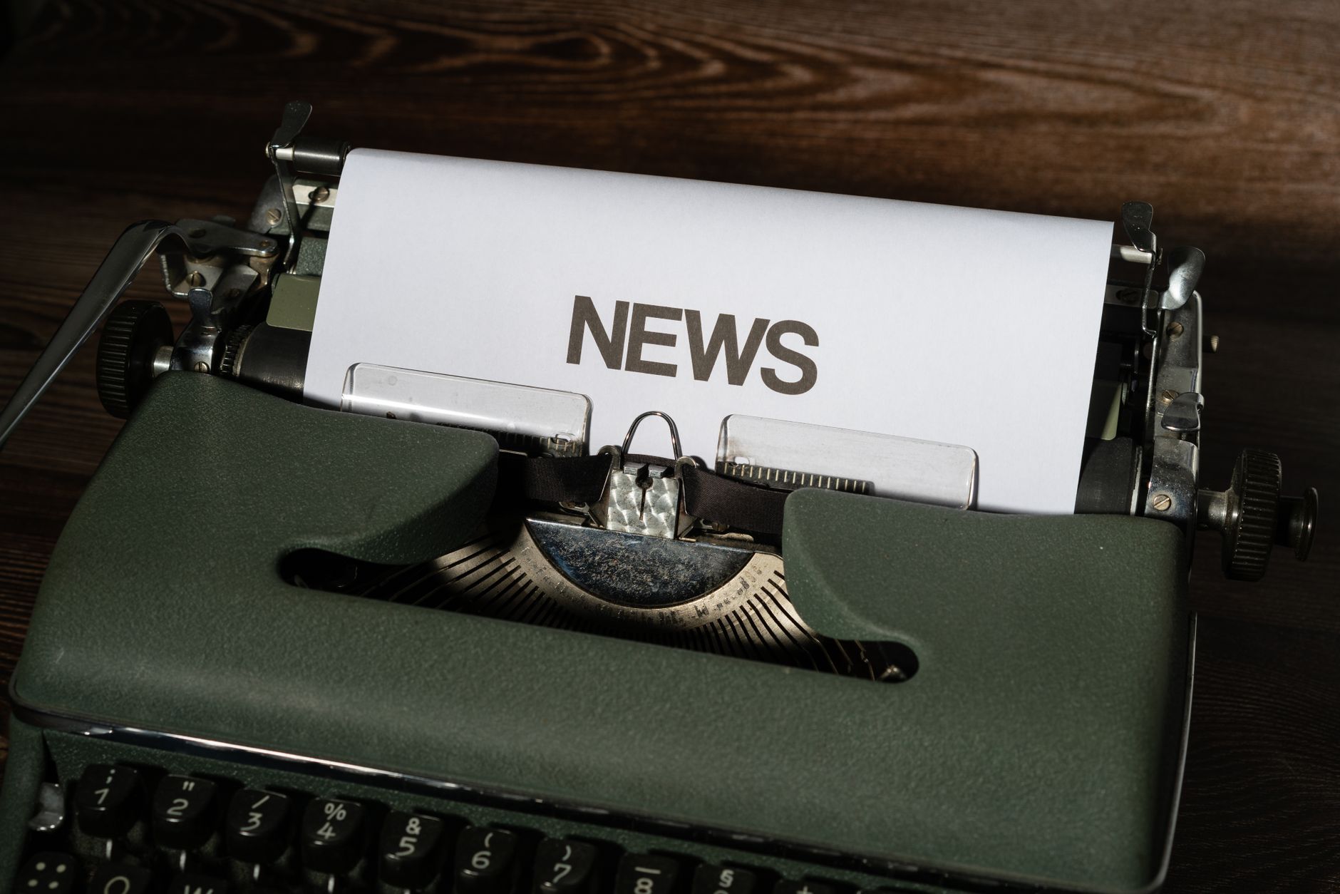 A retro typewriter featuring a 'NEWS' headline typed on white paper against a wooden surface. — God of Coins Casino im Test: